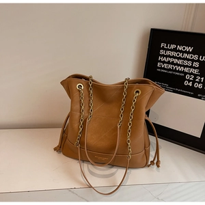 Detailed shot of brown tote bag with V-shaped stitching and golden chain strap