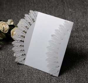 Close-up of laser-cut feather patterns on elegant white pearlescent paper wedding invitation