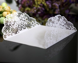 Detailed laser-cut lace pattern on elegant white wedding invitation card cover