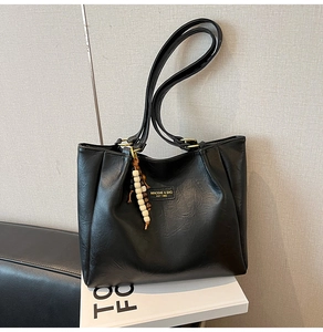 Détail du cabas noir avec écusson en cuir et pendentif vintage en perles de bois