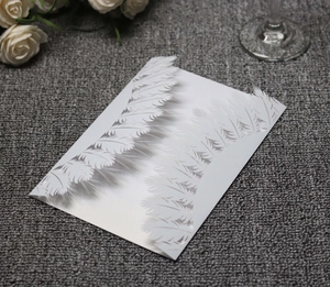 Close-up of laser-cut white feather pattern on premium pearlescent paper invitation