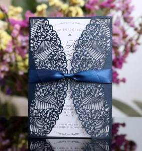 Detail of laser-cut navy blue wedding invitation with elegant satin ribbon and printed insert