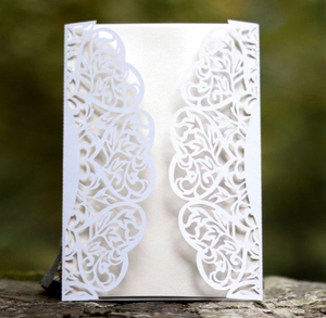 Detailed laser-cut intricate vine patterns on white wedding invitation card