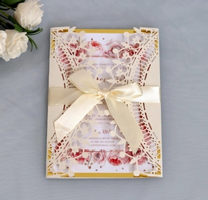 Detail of red laser-cut wedding invitation with crown lace and champagne satin ribbon