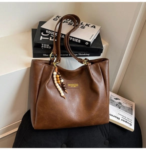 Détail du sac cabas en cuir marron vintage avec pendentif en bois et anneaux dorés