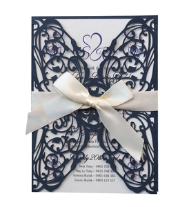 Detail of laser-cut navy blue butterfly wedding invitation with ribbon and printed insert