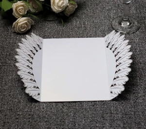 Macro view showing intricate laser-cut white feather patterns on wedding invitation paper