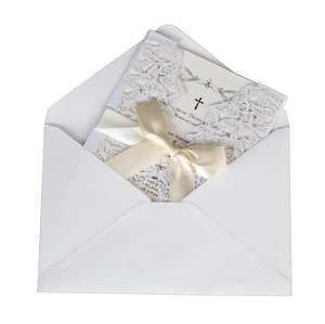 Detail of laser-cut butterfly invitation card with cream ribbon and white envelope