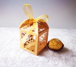 Close-up of laser-cut musical note candy box with a yellow ribbon bow and gold chocolate