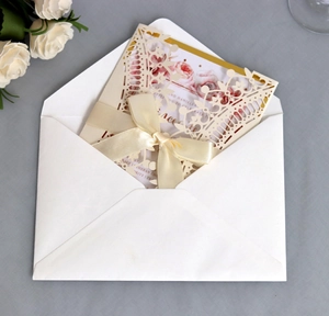 Detail of red laser cut lace invitation with cream insert and champagne satin ribbon bow