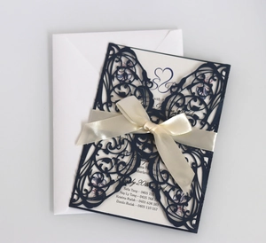 Detailed view of laser-cut wedding invitation with navy shell and cream satin bow
