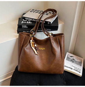 Détail du sac cabas en cuir marron caramel avec plis et breloque en perles de bois