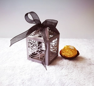 Close-up of laser-cut musical note gift box with silver cardstock and black ribbon bow