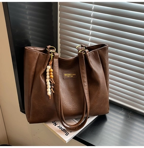 Détail du sac cabas marron vintage avec texture cuir, étiquette et perle en bois
