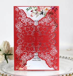 Detail of red laser cut lace wedding invitation with floral insert and elegant patterns