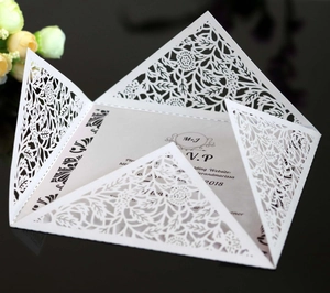 Macro view of white laser-cut floral wedding invitation with detailed hollow pattern