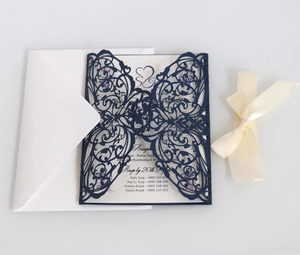 Detail of laser-cut navy blue wedding invitation with white insert and cream satin ribbon