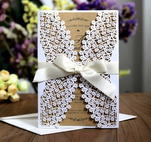 Detailed laser-cut petal wedding invitation set with cream ribbon and kraft paper on wood
