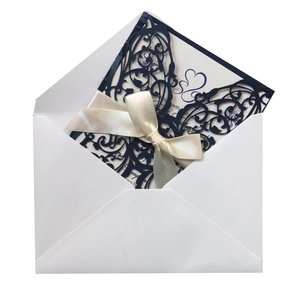 Detail of laser-cut butterfly wedding invitation set with navy blue cover and cream ribbon