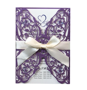 Detailed laser-cut purple wedding invitation with white satin bow and elegant floral patterns