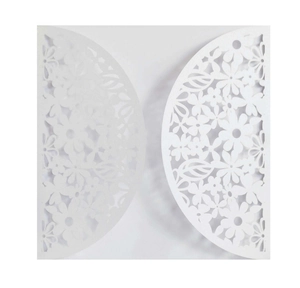 Close-up of white laser-cut floral wedding invitation with intricate hollow details