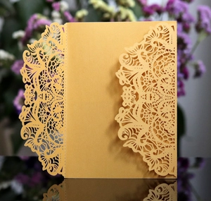 Detail of laser-cut golden mandala pearl paper wedding invitation cover with intricate hollow pattern