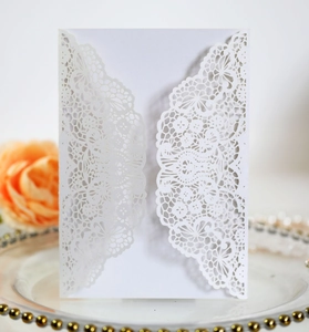 Macro shot of laser-cut lace floral pattern on white pearlescent wedding invitation card