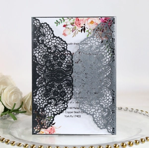 Detail of laser-cut lace wedding invitation with floral insert on elegant background