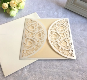 Détail d'invitation de mariage ajourée en forme de cœur crème avec carte et enveloppe