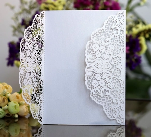 Macro shot of white laser-cut lace floral pattern on pearlescent paper invitation