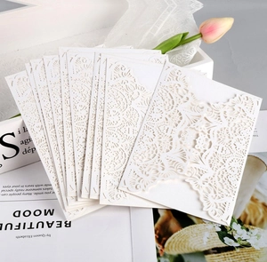 Detail of white laser-cut lace wedding invitation covers with elegant floral patterns