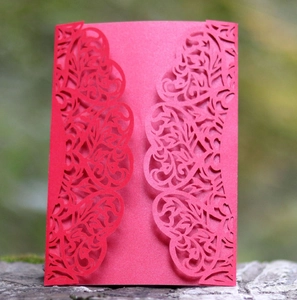 Detail of red laser-cut hollow card with intricate floral patterns on a wooden stand
