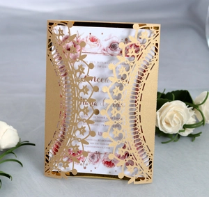 Macro view of laser-cut hollow lace patterns on a gold wedding invitation cover