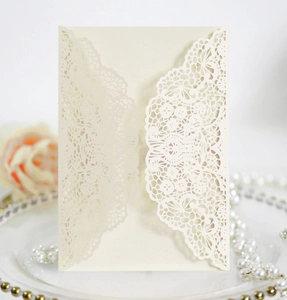 Detail of laser-cut lace wedding invitation with elegant cream floral patterns