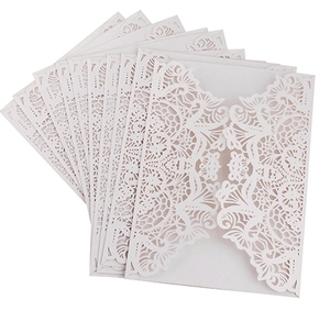Macro shot of pearl white laser-cut lace floral patterns on elegant wedding invitations