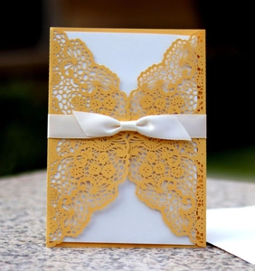 Lace laser-cut wedding invitation card with yellow floral patterns and a white silk bow