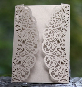 Detail of laser-cut vine patterns on champagne gold pearlescent paper invitation card