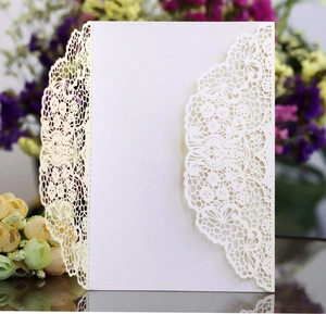 Detailed close-up of white laser-cut lace floral pattern on wedding invitation card