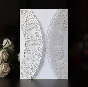 Detail of laser-cut pearl white wedding invitation with intricate leaf patterns