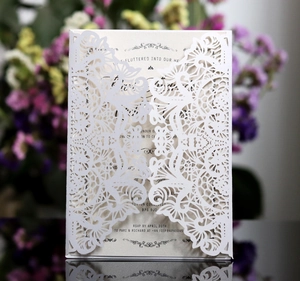 Detailed laser cut wedding invitation featuring intricate white butterfly and floral patterns
