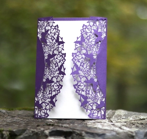 Detail of purple laser-cut wedding invitation with elegant butterfly and floral lace patterns