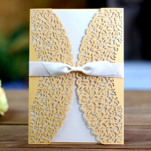 Elegant laser-cut wedding invitation with gold lace floral pattern and white silk ribbon