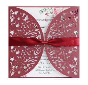Detailed laser-cut floral wedding invitation in burgundy with red ribbon and insert card