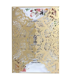 Macro view of laser-cut gold glitter wedding invitation with intricate lace hollow patterns
