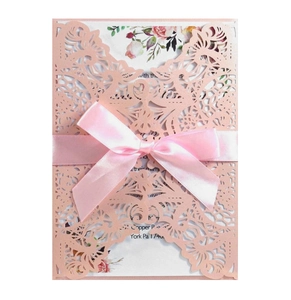 Close-up of laser-cut invitation sleeve with floral watercolor insert and silk ribbon