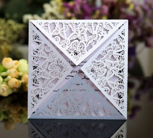 Close-up of laser-cut butterfly wedding invitation with elegant white lace and purple insert