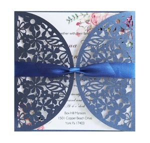 Detail of laser cut navy blue wedding invitation with satin ribbon and floral insert