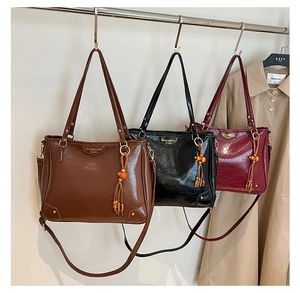 Detailed display of three vintage tote bags with bead tassel charms and metal brand tags