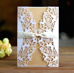 Close-up of laser-cut wedding invitation with butterfly lace and cream silk ribbon