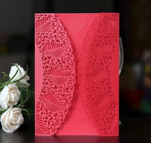 Detail view of the intricate laser-cut leaf pattern on the red wedding invitation card